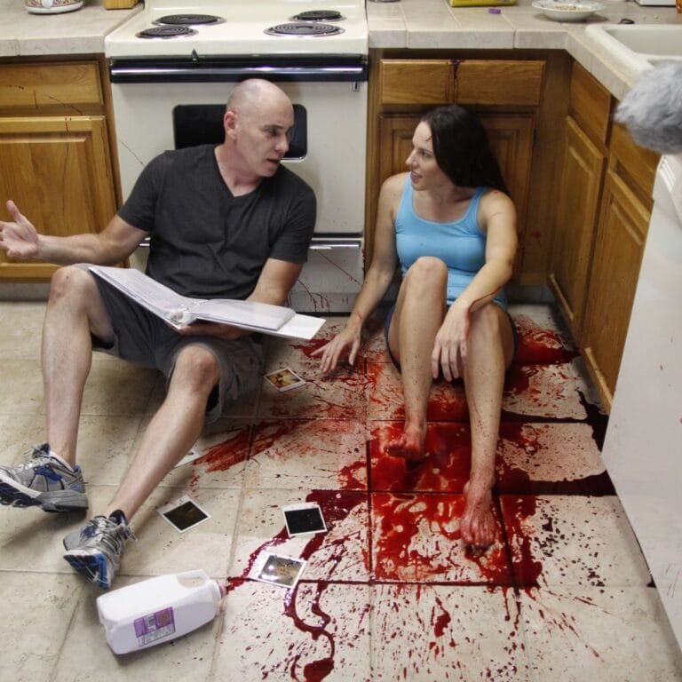 a man and woman sitting on the floor with blood on the floor