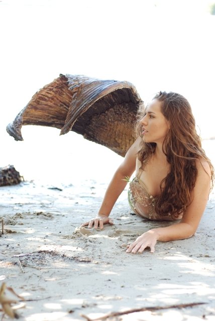 a woman lying on the sand with a mermaid tail