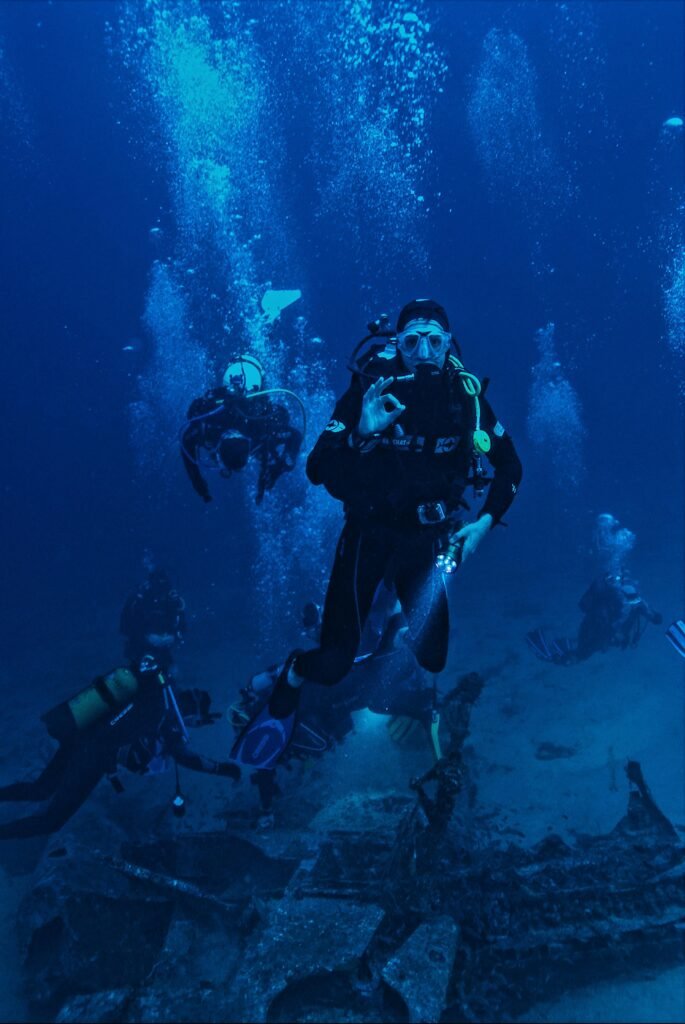 A group of scuba divers exploring a submerged shipwreck in the ocean.