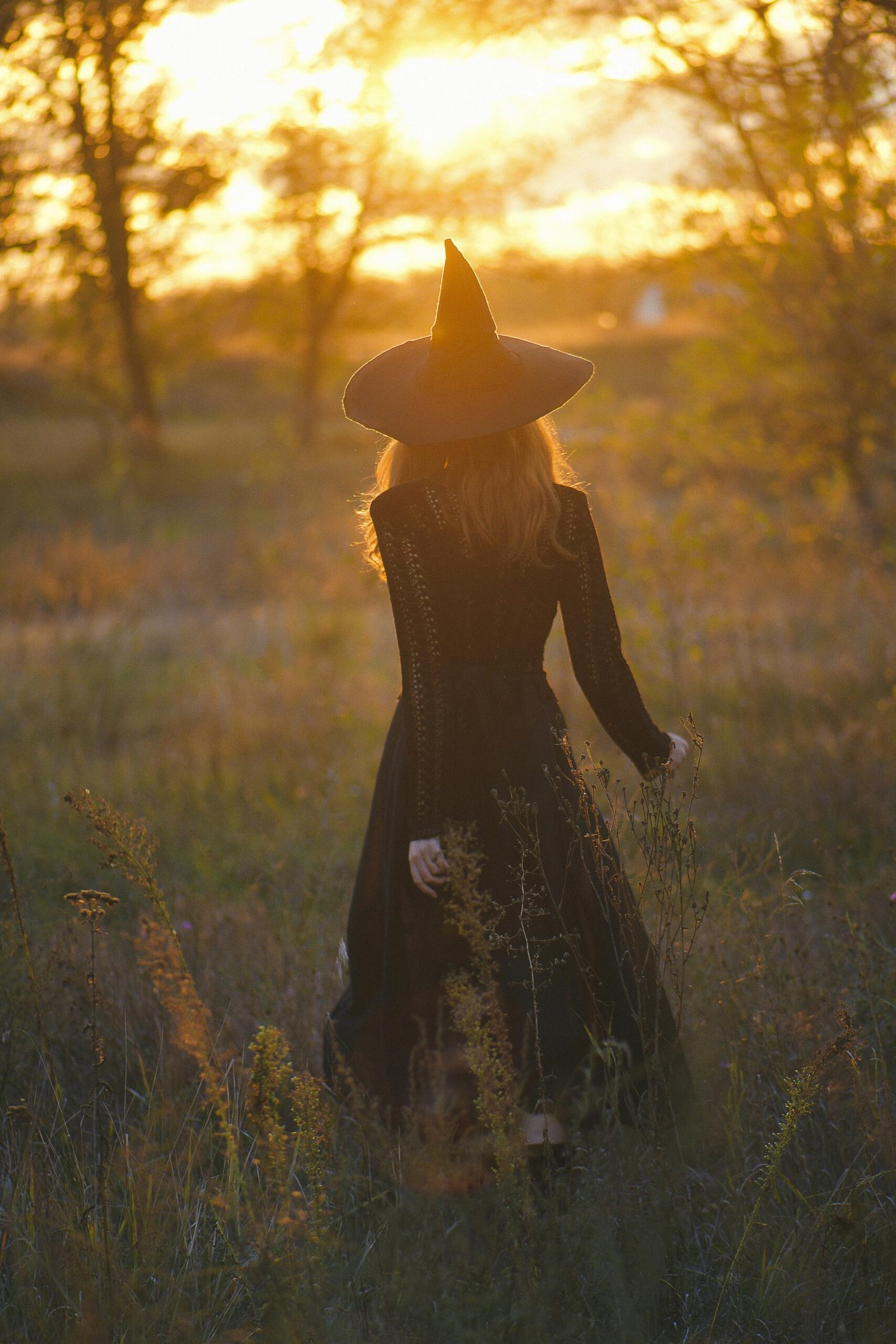 5 Powerful Ways to Shine as a Creative Misfit (Even When You Feel Left Out) 6 A woman in a witch costume walks through a field at sunset, evoking a mystical autumn atmosphere to meet up with ghouls, ghosts and mermaids at a spooky Halloween Mermaid Retreat Shellebration.