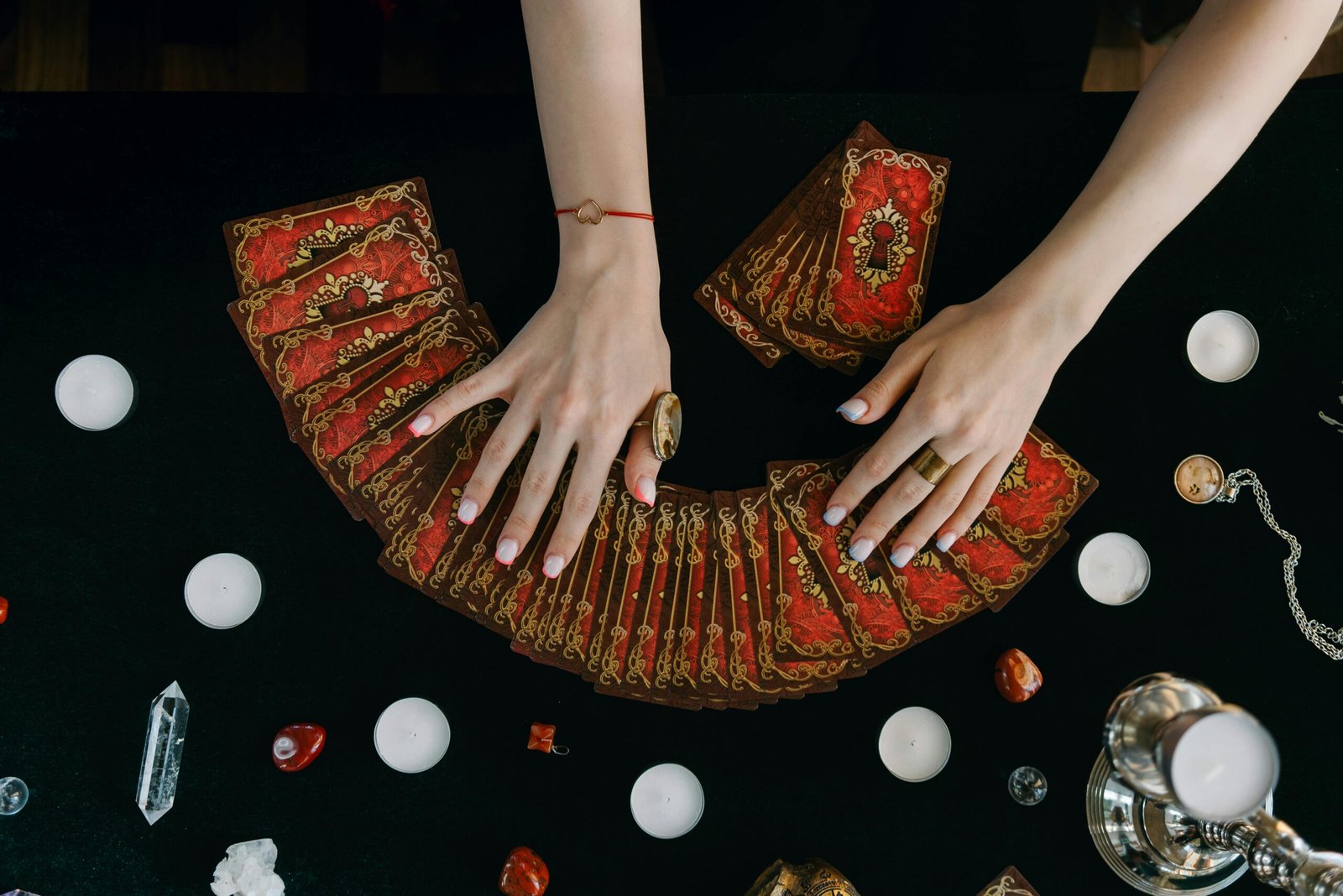 Hands arranging tarot cards on a table surrounded by candles and crystals, creating a mystical ambiance symbolizing the healing power of play and connection.