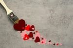 A paintbrush with red hearts, symbolizing love and commitment through creativity.
