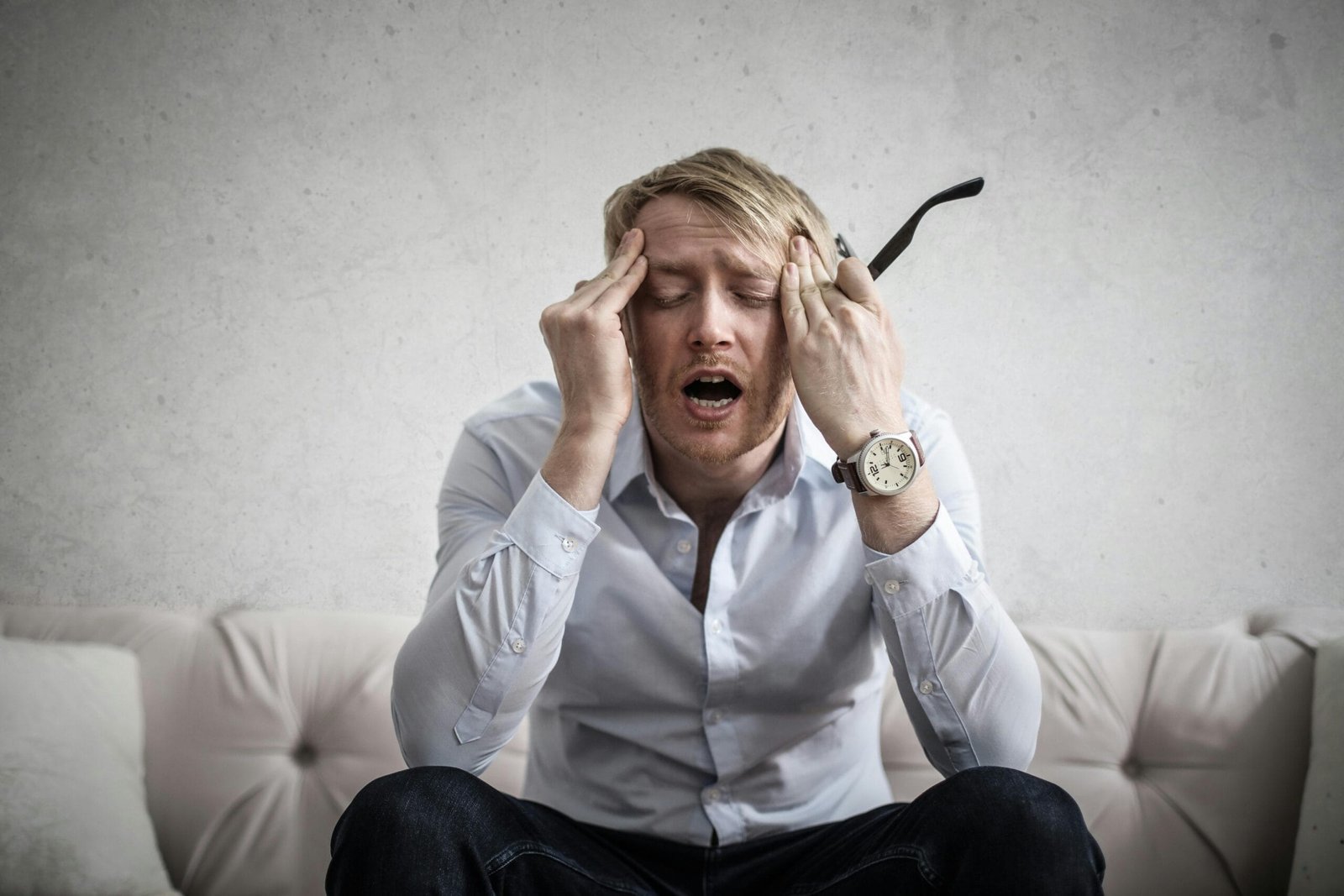 The Pay‑to‑Play Hustle: What It Really Costs to Be a Working Actor 5 Stressed man sitting on couch, feeling overwhelmed and frustrated, expressing mental strain showing the frustration of actors continuous investments