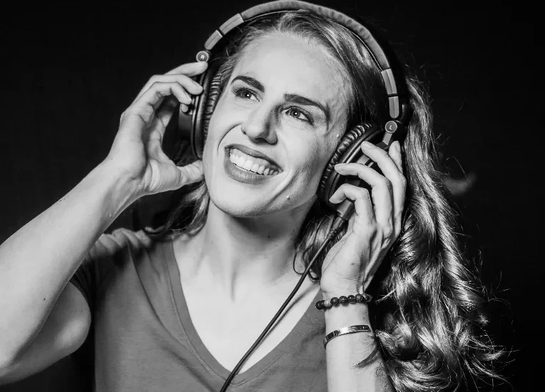 Female voice actor Shannon Scott recording in a professional studio booth.