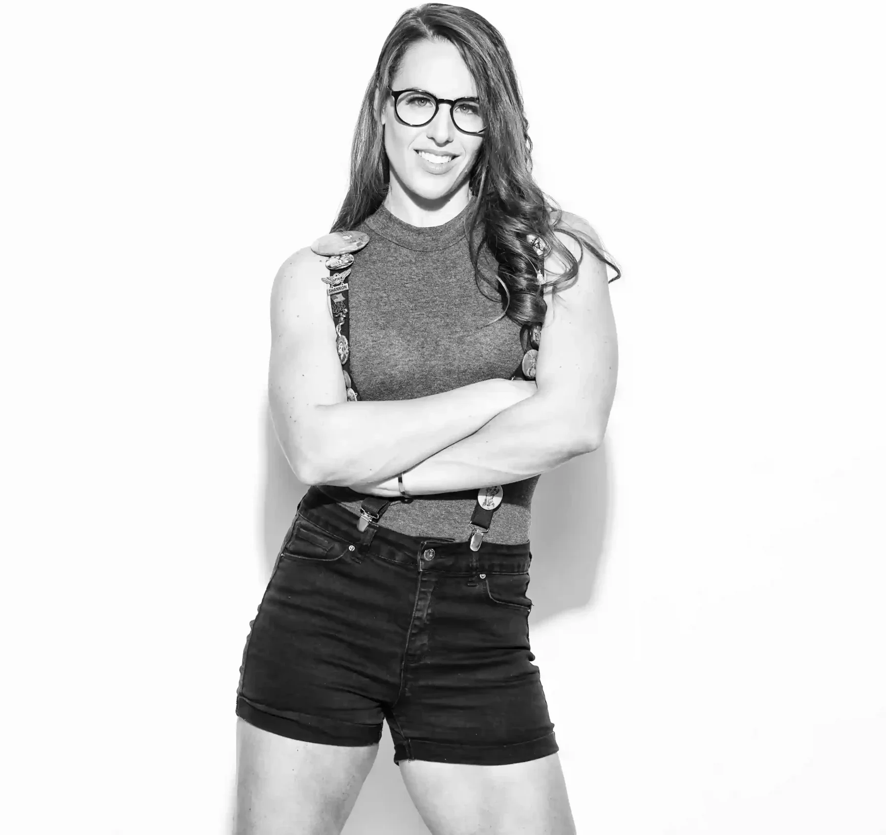 Get In Touch with Shannon Scott: Voiceover, Acting, and Underwater Performance That Brings Stories to Life 5 Black-and-white portrait of Shannon Scott, a female voice artist, wearing glasses and denim overalls with flare buttons, posing confidently with a creative and expressive look.