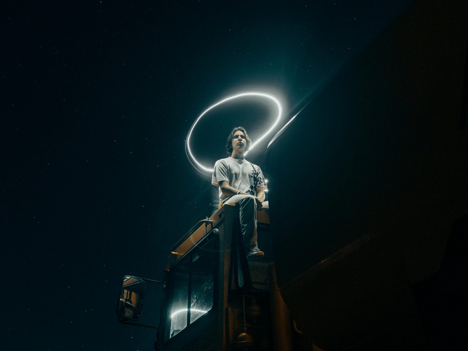 Magical artist sitting on a truck with a ring light hovering above him, embodying creative focus and imagination.