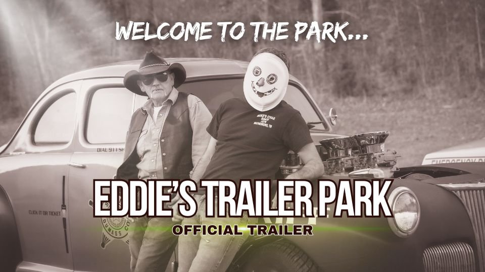 Crook and sheriff standing beside the sheriff’s hotrod in a trailer park scene from the dark comedy film Eddie’s Trailer Park.