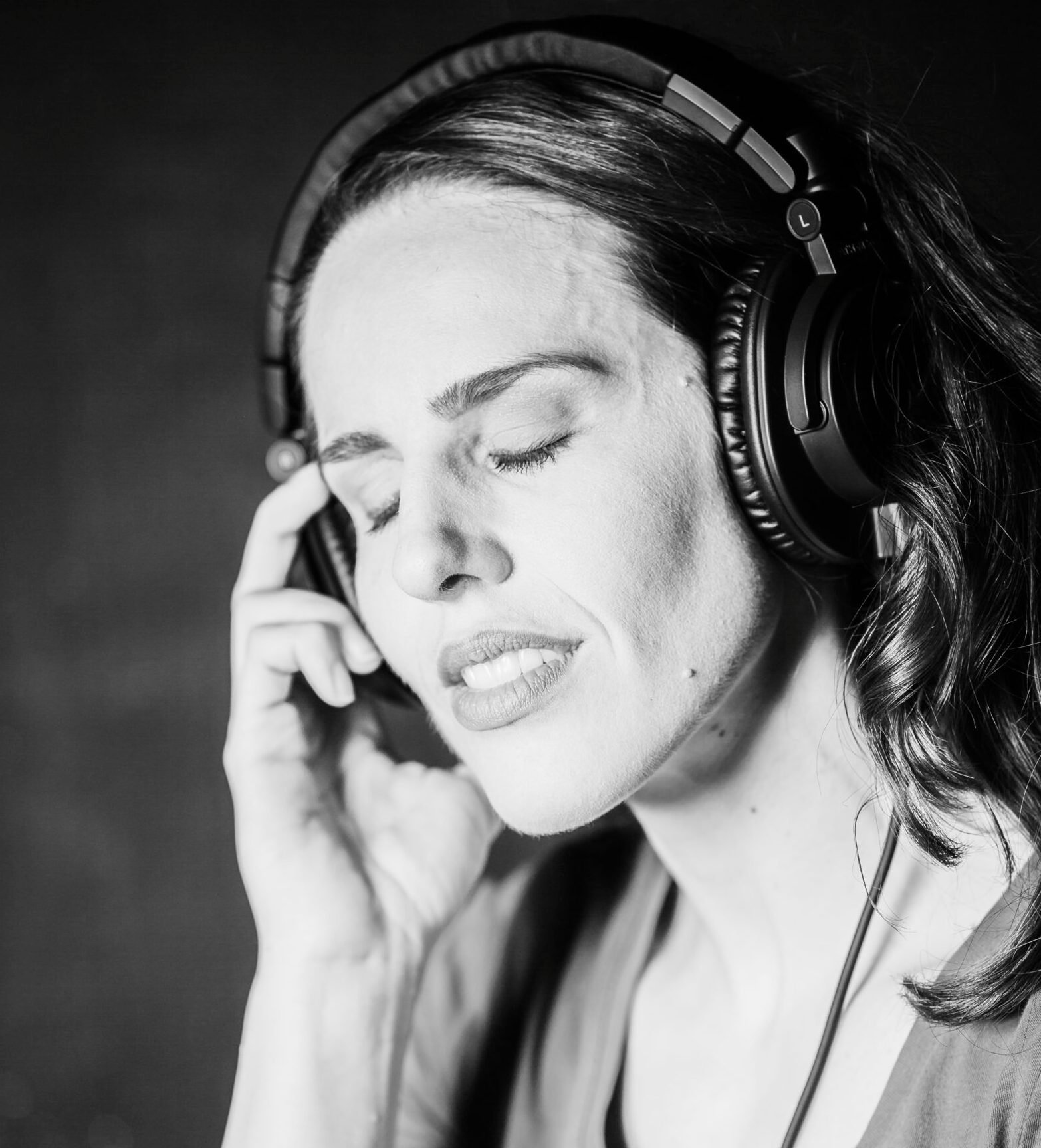 A professional in headphones with eyes closed, focused on listening during a medical voiceover recording session