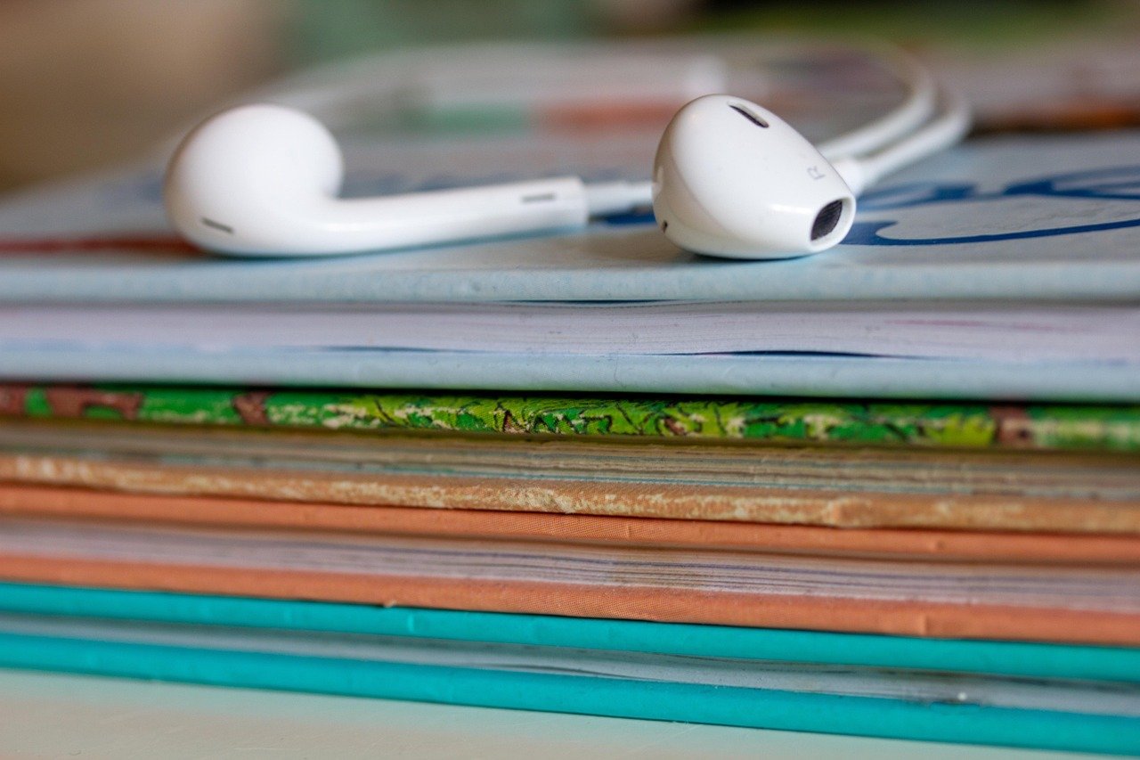 Earbuds resting on books representing voice over demos for audiobook and longform narration