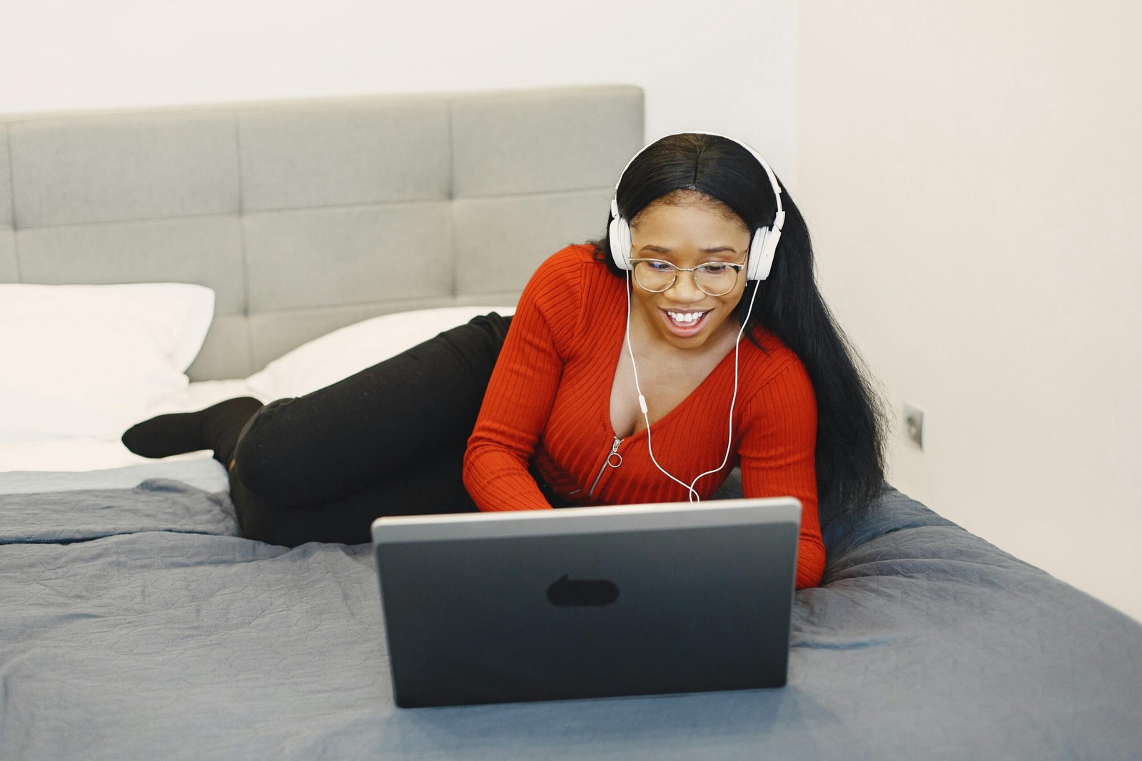 Why Professional Voice Over Services Build Trust With Your Audience 4 Woman relaxing on bed with headphones watching laptop, illustrating professional voice over services used in digital learning and content engagement